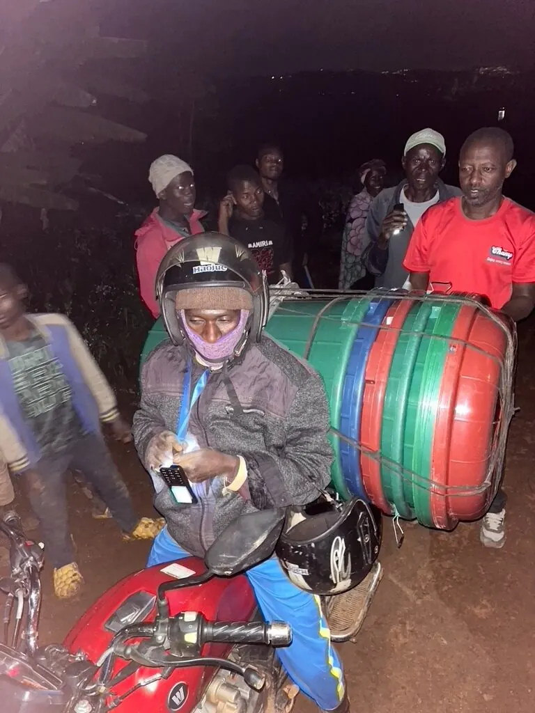 A moto driver carrying stacked Amazi tanks and fittings
